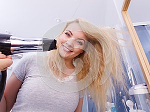 Woman drying hair in bathroom