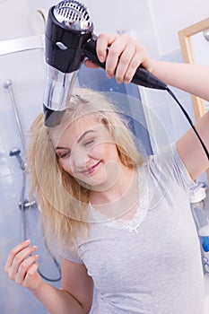 Woman drying hair in bathroom