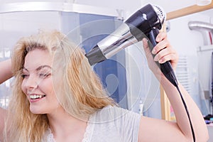 Woman drying hair in bathroom