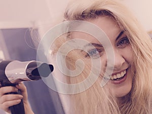 Woman drying hair in bathroom