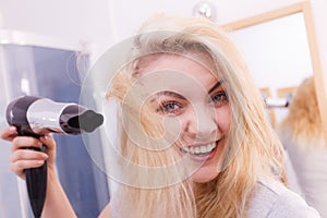 Woman drying hair in bathroom