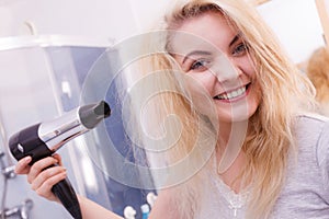 Woman drying hair in bathroom