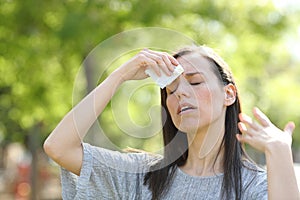 Woman drying sweat using a wipe in a warm summer day photo
