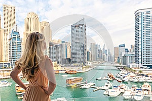 Woman in Dubai Marina, United Arab Emirates. Attractive lady wearing a long dress admiring Marina daylight views