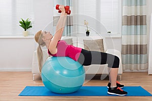 Woman With Dumbbell While Exercising On Fitness Ball