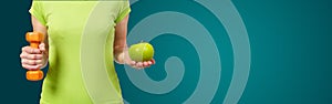 Woman with dumbbells and apple on green background