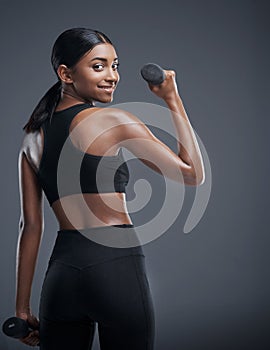 Woman, dumbbells and smile for workout in studio on grey background for health, muscles and sportswear. Back view