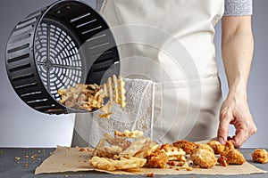 A woman is dumping fresh made potato waffle fries from basket onto a countertop