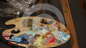 Woman dunking paintbrush in palette with oil paints, art workmanship, hobby