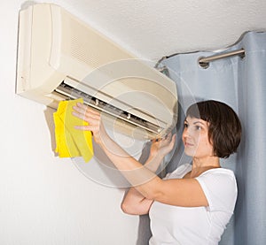 Woman dusting air conditioning