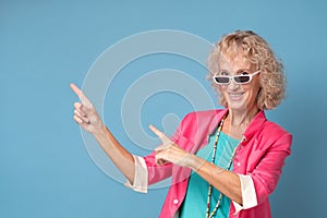 Woman with sunglasses smiling cheerfully and pointing with forefingers away photo