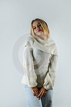 woman with dyed hair and healthy skin dressed stylishly smiling posing against white wall.