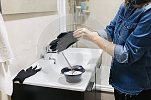 A woman dyes her hair at home.