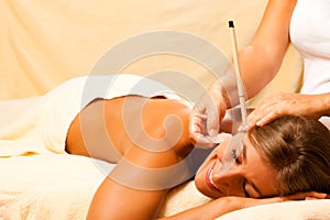 Woman with ear candles and gem massage