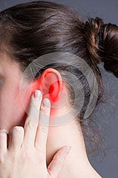 Woman with earache, ear pain on gray background