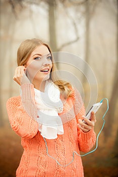 Woman with earphones listening to music in park.