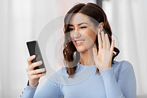 woman with earphones and smartphone at home
