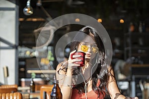 Woman with earphones using digital tablet while drinking a cup of coffee at a coffee shop