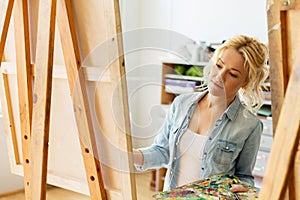Woman with easel painting at art school studio