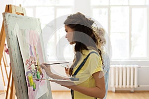 Woman with easel painting at art school studio