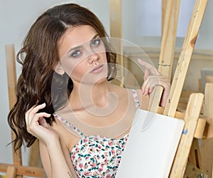 Woman with easel, palette and brush painting at art studio