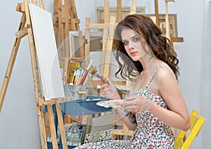 Woman with easel, palette and brush painting at art studio