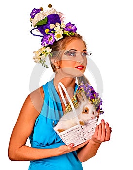 Woman in easter style holding rabbit and flowers in basket.