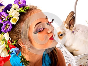 Woman in easter style kissing rabbit and flowers in basket.