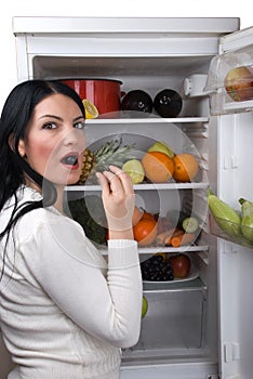 Woman eat a berry grape from fridge