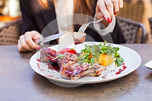 Woman eat healthy lunch in restaurant. Grilled meat steak with cranberry sauce, glazed peaches and arugula salad