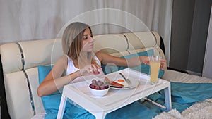 Woman Eating Breakfast Sausages With Scrambled Eggs On The Table, Lying In Bed