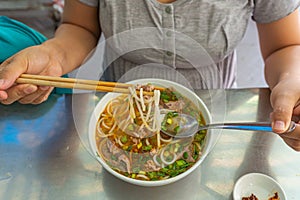 Woman eating Bun Bo Hue, delicious Vietnamese food