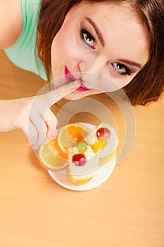 Woman eating cake showing quiet sign. Gluttony.