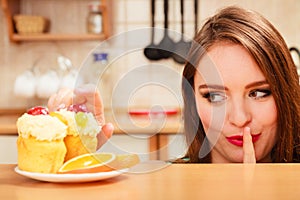 Woman eating cake showing quiet sign. Gluttony. photo
