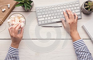 Woman eating candies at workplace, top view