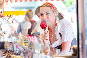 Woman eating candy apple at Oktoberfest or Dult