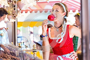 Woman eating candy apple at Oktoberfest or Dult