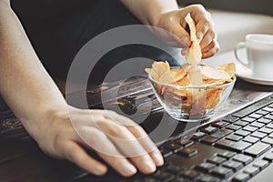 Woman eating chips from bowl at her workplace