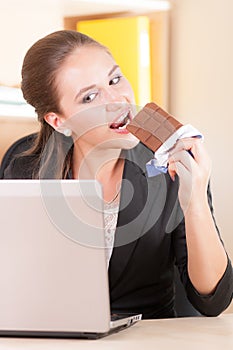 Woman eating chocolade in office