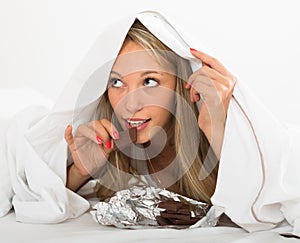 Woman eating chocolate in bed