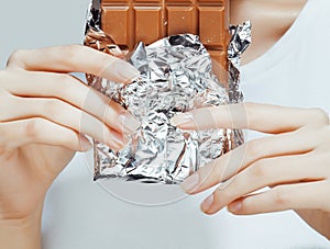 Woman eating chocolate, close up hands with manicure french nails holding candy, beautiful fingers