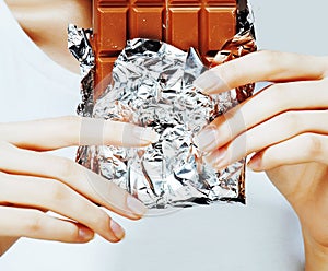 Woman eating chocolate, close up hands with manicure french nails holding candy, beautiful fingers, lifestyle concept