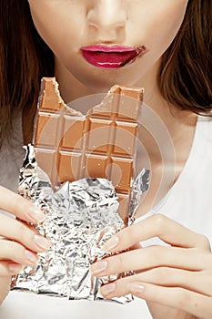 Woman eating chocolate, close up hands with manicure french nails holding candy, beautiful fingers