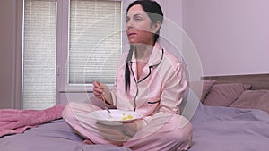 Woman eating cornflakes in bed.Breakfast