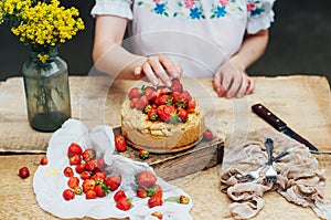 Woman eating a delicious home-made cake with aisheny and stuffed strawberries for dessert. Summer Styled dinner table. Coffee to