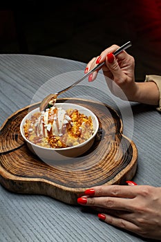 Woman eating dessert in a restaurant. Dessert on a wooden stand. Close-up of hands.
