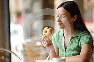 Woman eating doughnut in a terrace