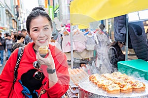 Woman eating Egg bread with almond, peanut and sunflower seed at Myeong-dong street food, Seoul, South Korea photo