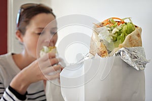 Woman eating Falafel warp in a street food restaurant