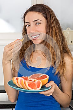 Woman eating fresh grapefruit slices